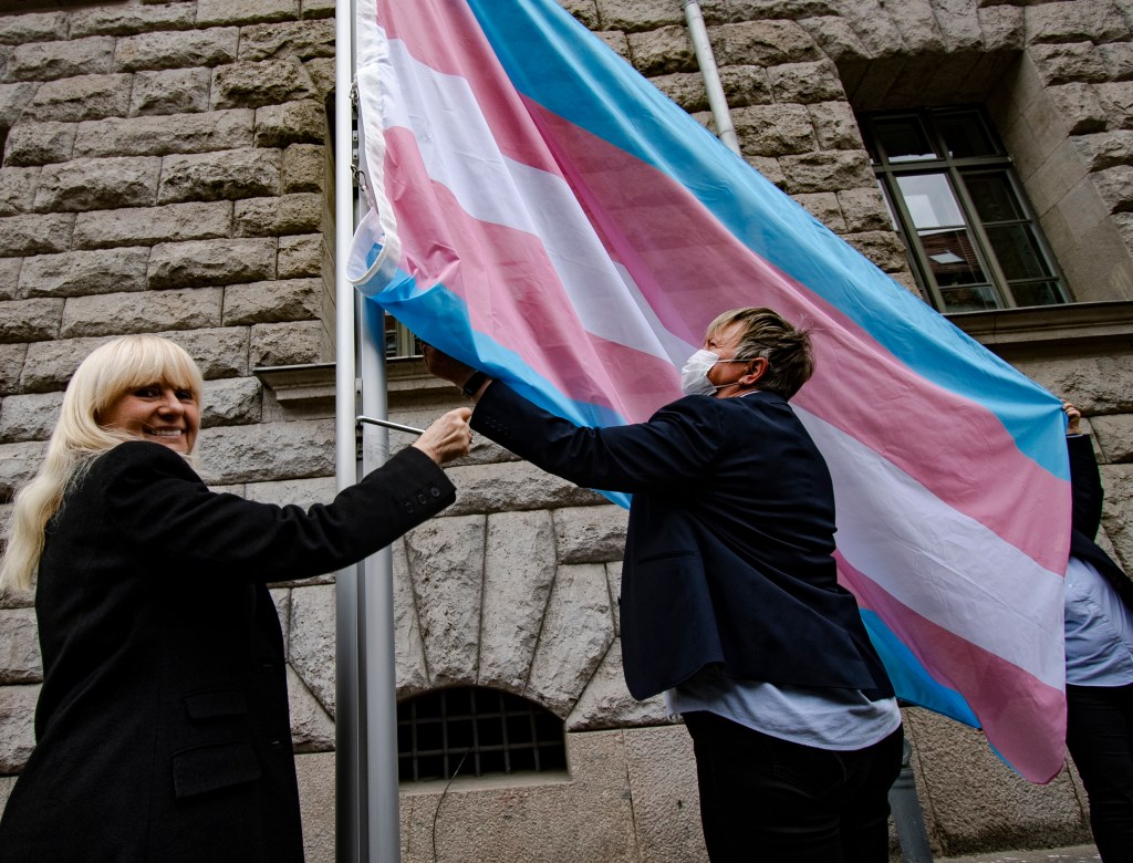 30 March 2022, Berlin: Iris Spranger (l, SPD), Senator of the Interior of Berlin, raises the trans flag in front of her office during a press event on the eve of the Transgender Day of Visibility. Photo: Paul Zinken/dpa (Photo by Paul Zinken/picture alliance via Getty Images)