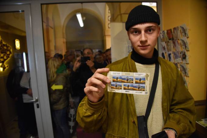 A man holds the newly purchased stamps “Russian warship DONE