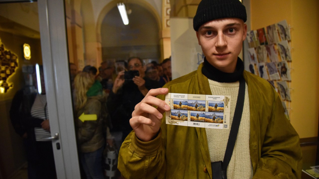 A man holds the newly purchased stamps "Russian warship DONE