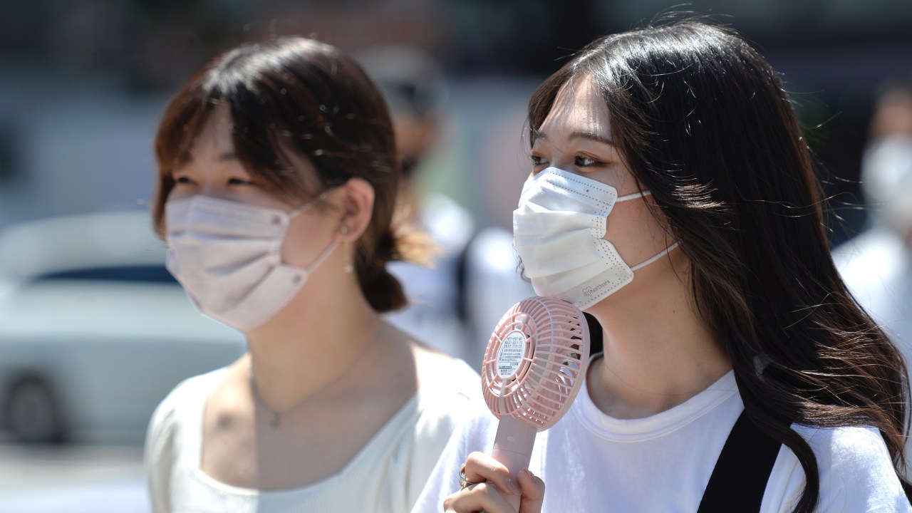 TOKYO, JAPAN - JUNE 27: A young woman is seen on the street using a portable fan to refresh herself on June 27, 2022, in Tokyo's popular Shibuya district in Tokyo, Japan. The capital of Japan has been swept by a heat wave for the past few days with temperatures well above 30 degrees Celsius. (Photo by David Mareuil/Anadolu Agency via Getty Images)