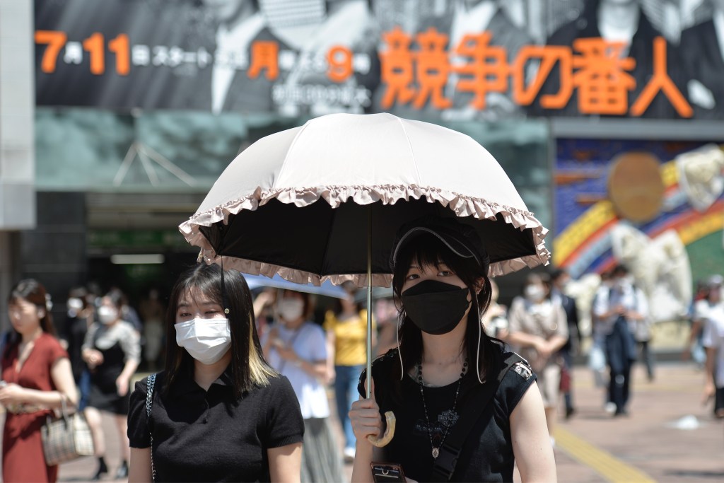 TOKYO, JAPAN - JUNE 27: People walk on the street using an umbrella to protect themselves from the sun on June 27, 2022, in Tokyo's popular Shibuya district in Tokyo, Japan. The capital of Japan has been swept by a heat wave for the past few days with temperatures well above 30 degrees Celsius. (Photo by David Mareuil/Anadolu Agency via Getty Images)