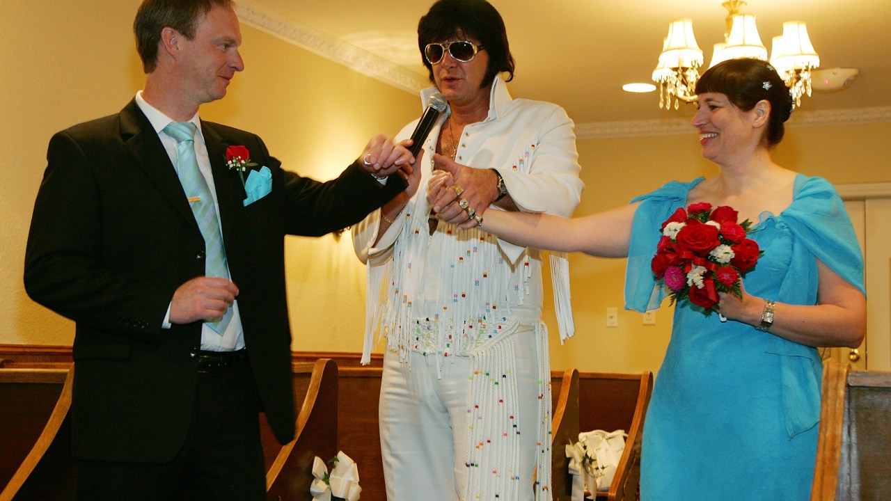 LAS VEGAS - JULY 07: Elvis Presley impersonator Jeff Stanulis (C) joins the hands of Anders Brusgard (L) and Ingela Bonstrom (R) of Sweden during their wedding ceremony at the Graceland Wedding Chapel July 7, 2007 in Las Vegas, Nevada. Wedding planners say a flood of couples are marrying on 7/7/07 due to the numerical and superstitious significance of the date. (Photo by Ethan Miller/Getty Images)