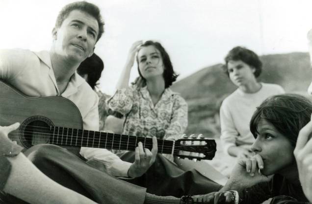 O músico João Gilberto tocando violão na praia do Arpoador, para Nara Leão e outras amigas, anos 60.