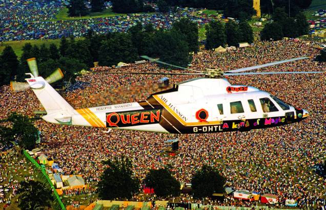 Helicóptero com os integrantes do Queen sobrevoa pela multidão de fãs, no Knebworth Park, na Inglaterra, 1986. Helicóptero com os integrantes do Queen sobrevoa pela multidão de fãs, no Knebworth Park, na Inglaterra, 1986.