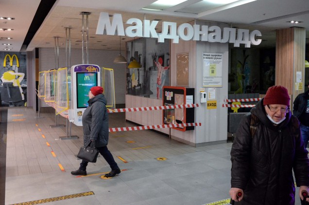 16/03/2022, pessoas caminham ao lado de um restaurante McDonald's fechado em um shopping center em Moscou.