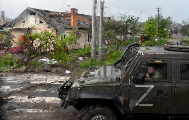 Um veículo militar russo pintado com a letra Z passa por casas destruídas na cidade portuária de Mariupol, na Ucrânia, em 18/05/2022, em meio à dominação militar russa em andamento na Ucrânia.