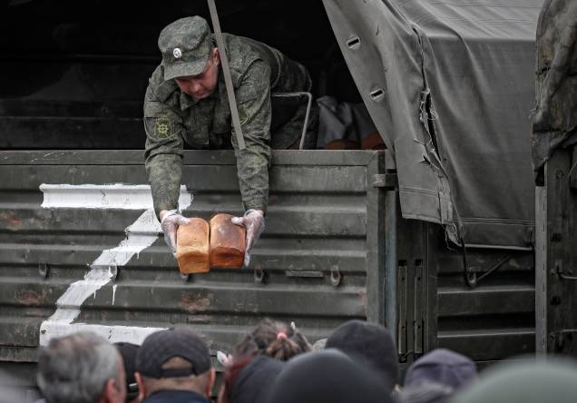 Dominada pelos soldados russos, militares distribuem pães como ajuda humanitária para a população local em Mariupol, Ucrânia, 12/05/2022.