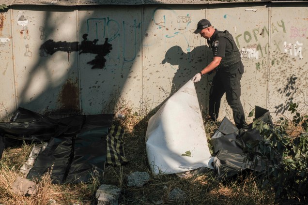 Agente de segurança ucraniano cobre o corpo de uma vítima, após bombardeio em uma área residencial em Mykolaiv, sul da Ucrânia, 29/06/2022.