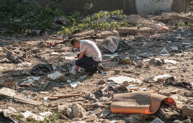 Um homem examina fotos sobre os escombros após bombardeio em uma área residencial em Mykolaiv, sul da Ucrânia, 29/06/2022.