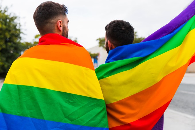couple-gay-wrapped-in-lgbt-flags-standing-back