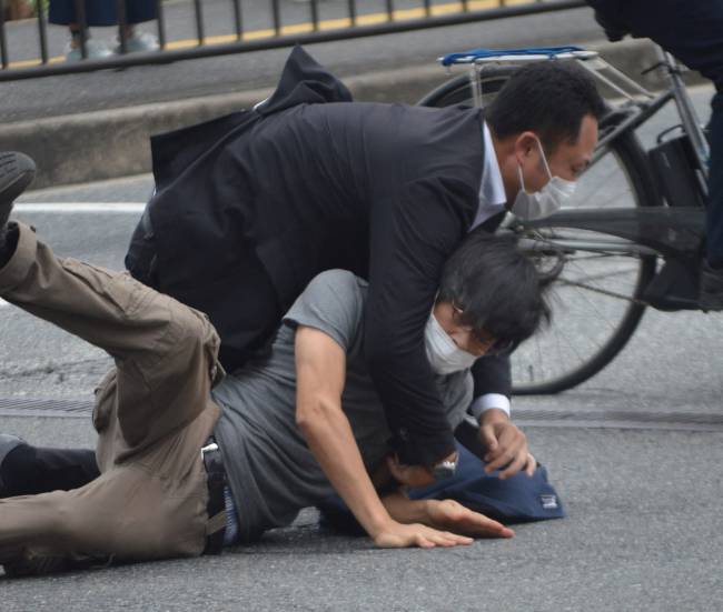 A man (bottom) suspected of shooting former Japanese prime minister Shinzo Abe is tackled to the ground by police at Yamato Saidaiji Station in the city of Nara on July 8, 2022. - Shinzo Abe was shot at a campaign event on July 8, a government spokesman said, as local media reported the nation's longest-serving premier was showing no vital signs. (Photo by Yomiuri Shimbun / AFP) / Japan OUT / NO ARCHIVES