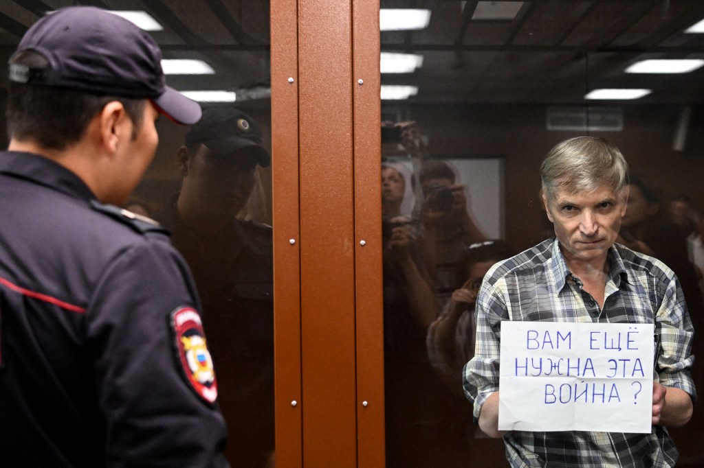 Moscow city deputy Alexei Gorinov, accused of spreading "knowingly false information" about the Russian army fighting in Ukraine, stands with a poster reading ""Do you still need this war?" inside a glass cell during the vedict hearing in his trial at a courthouse in Moscow on July 8, 2022. (Photo by Kirill KUDRYAVTSEV / AFP)