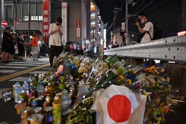 A man pays his respects in front of a makeshift memorial outside Yamato-Saidaiji Station, where former Japanese prime minister Shinzo Abe was shot earlier in the day, in Nara on July 8, 2022. - Abe was pronounced dead on July 8, the hospital treating him confirmed, after he was shot at a campaign event in the city of Nara. (Photo by Philip FONG / AFP)
