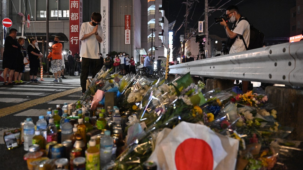 A man pays his respects in front of a makeshift memorial outside Yamato-Saidaiji Station, where former Japanese prime minister Shinzo Abe was shot earlier in the day, in Nara on July 8, 2022. - Abe was pronounced dead on July 8, the hospital treating him confirmed, after he was shot at a campaign event in the city of Nara. (Photo by Philip FONG / AFP)