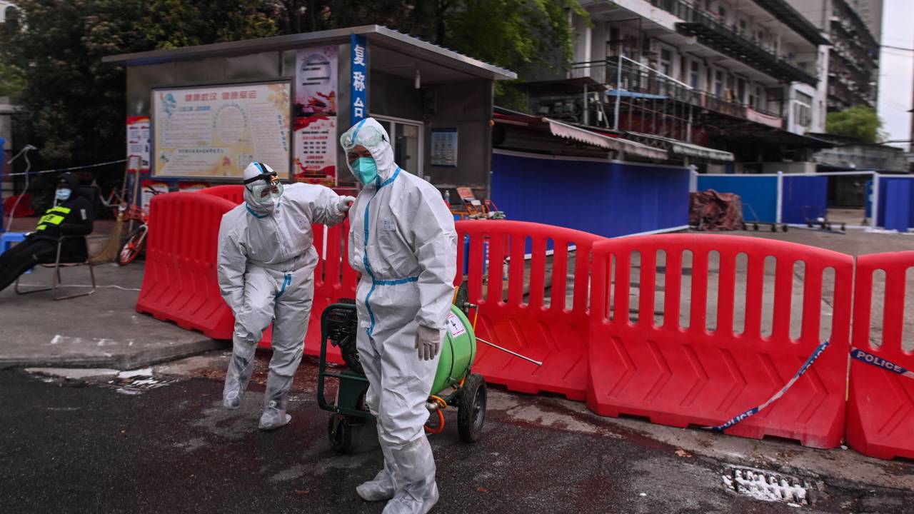 (FILES) In this file photo taken on March 30, 2020, workers wearing protective suit walk next to Huanan Seafood Wholesale Market in Wuhan, in China's central Hubei province. - The Huanan Seafood Wholesale Market really was the epicenter of the Covid pandemic, according to a pair of new studies in the journal Science published on July 26, 2022, that claimed to have tipped the balance in the debate about the virus' origins. Answering the question of whether the disease spilled over naturally from animals to humans, or was the result of a lab accident, is viewed as vital to averting the next pandemic and saving millions of lives. The first paper analyzed the geographic pattern of Covid cases in the outbreak's first month, December 2019, showing the first cases were tightly clustered around the market. (Photo by Hector RETAMAL / AFP)