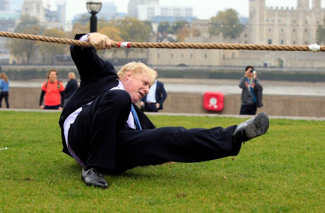 O então prefeito de Londres, Boris Johnson, cai durante uma disputa de cabo de guerra com funcionários da Marinha Real, do Exército e da Força Aérea Real, em  Londres, 27/10/2015.