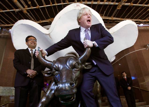O então prefeito de Londres Boris Johnson posa com a estátua de bronze de um touro ao lado da Bolsa de Valores de Bombaim, Índia, em 30/11/2012.