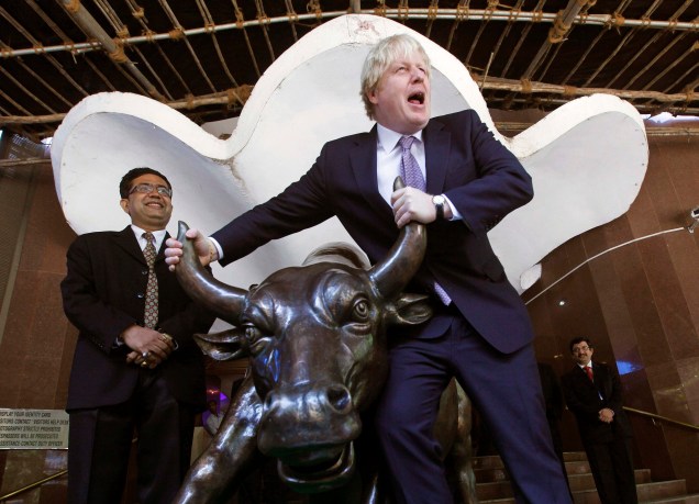 O então prefeito de Londres Boris Johnson posa com a estátua de bronze de um touro ao lado da Bolsa de Valores de Bombaim, Índia, em 30/11/2012.