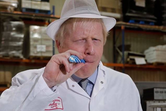 O primeiro-ministro da Grã-Bretanha, Boris Johnson, come um doce que diz "Back Boris" durante uma campanha eleitoral geral em Blackpool, Inglaterra, em 15/11/2019.
