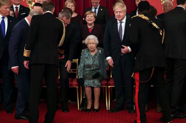 A rainha Elizabeth II da Grã-Bretanha, ao centro, senta-se com o primeiro-ministro britânico Boris Johnson e a chanceler da Alemanha Angela Merkel,  durante uma recepção formal para os chefes dos países da OTAN, no Palácio de Buckingham, em Londres, em 03/03/ 2019.