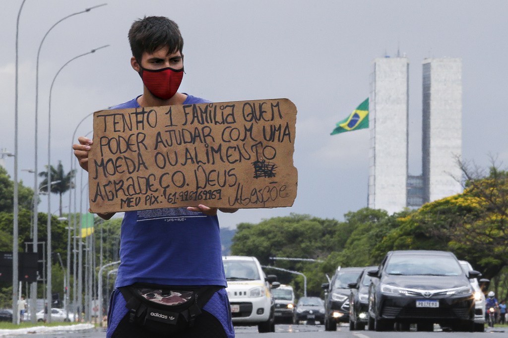 Homem pede ajuda para comer, em cena cada vez mais comum em Brasília. Cartazes do tipo viraram um símbolo da onda de fome no país -