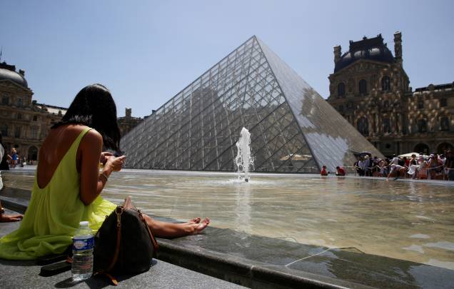 Um banhista senta-se na borda da fonte da Pirâmide do Louvre, em Paris, em 17/06/2022, enquanto uma onda de calor varre grande parte da França e da Europa.