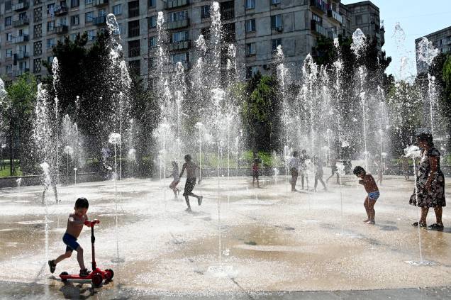 Pessoas se refrescam com a água de uma fonte em Tbilisi em 09/07/2022, quando a temperatura do ar se aproxima de 30 graus Celsius.