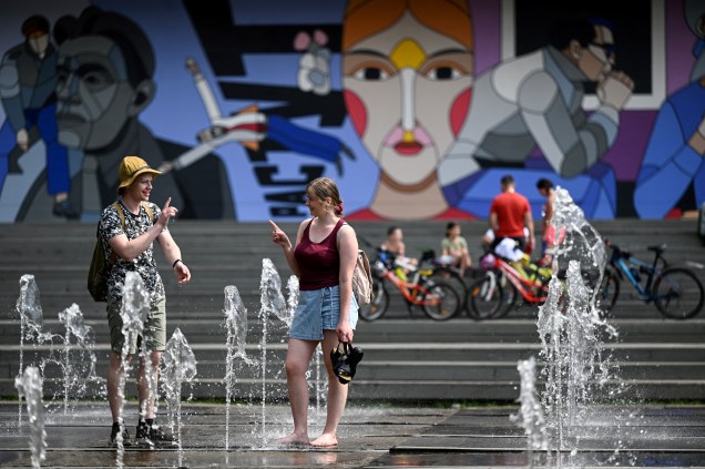Um casal se refresca com a água de uma fonte em Moscou, 05/07/2022, quando a temperatura se aproxima de 30 graus Celsius.