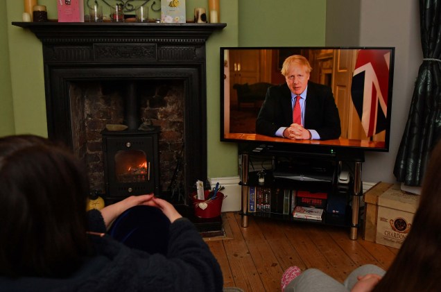 Membros de uma família ouvem o primeiro-ministro da Grã-Bretanha, Boris Johnson, fazer um discurso televisionado à nação de dentro da 10 Downing Street, em Londres, com as últimas instruções para ficar em casa para ajudar a conter a pandemia de Covid-19, de uma casa em Liverpool, Inglaterra em 23/03/2020.