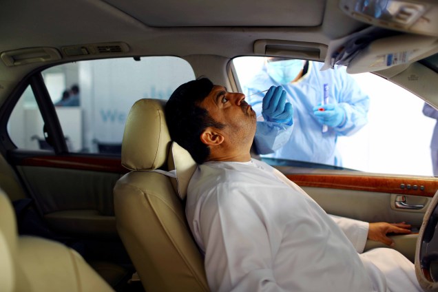 Um membro da equipe médica usando luvas de proteção realiza um teste de cotonete em um homem no teste drive-thru de coronavírus (COVID-19) em um centro de triagem em Abu Dhabi, Emirados Árabes Unidos, 30/03/2020. Um membro da equipe médica usando luvas de proteção realiza um teste de cotonete em um homem no teste drive-thru de coronavírus (COVID-19) em um centro de triagem em Abu Dhabi, Emirados Árabes Unidos, 30/03/2020.