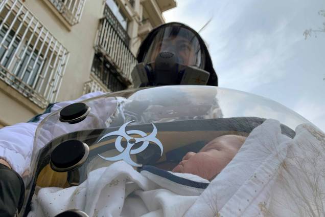Um pai com seu bebê de dois mêses dentro de uma cápsula de segurança que ele criou para protegê-lo da doença do novo coronavírus (COVID-19), em um complexo residencial em Xangai, China, 25/03/2020.