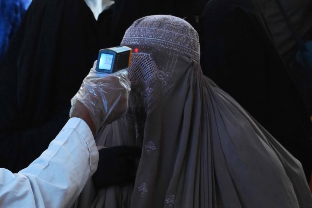 Uma autoridade de saúde verifica a temperatura corporal de uma mulher vestida de burca em meio a preocupações com a disseminação do novo coronavírus COVID-19 na estação ferroviária de Lahore, em Lahore, em 19/03/2020. Uma autoridade de saúde verifica a temperatura corporal de uma mulher vestida de burca em meio a preocupações com a disseminação do novo coronavírus COVID-19 na estação ferroviária de Lahore, em Lahore, em 19/03/2020.