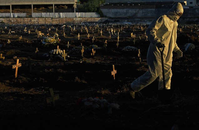Agente funerário vestindo roupas de proteção como medida preventiva contra o novo coronavírus, COVID-19, caminha pelo cemitério do Caju, no Rio de Janeiro, Brasil, em 09/05/2020.