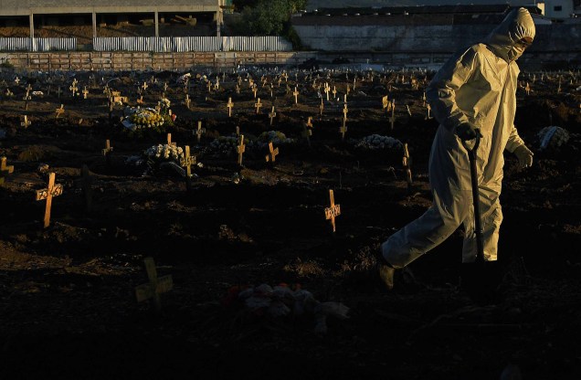 Agente funerário vestindo roupas de proteção como medida preventiva contra o novo coronavírus, COVID-19, caminha pelo cemitério do Caju, no Rio de Janeiro, Brasil, em 09/05/2020. Agente funerário vestindo roupas de proteção como medida preventiva contra o novo coronavírus, COVID-19, caminha pelo cemitério do Caju, no Rio de Janeiro, Brasil, em 09/05/2020.