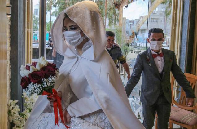 O noivo palestino Mohamed Abu Daga e sua noiva Israa usam máscaras protetoras em meio à epidemia de COVID-19, ao chegarem a um estúdio fotográfico antes da cerimônia de casamento, em Khan Yunis, no sul da Faixa de Gaza, em 23/03/ 2020.
