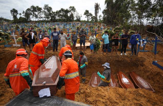 Coveiros carregam caixão durante enterro coletivo de pessoas que faleceram devido à doença do coronavírus (COVID-19), no cemitério Parque Taruma, em Manaus, Brasil, 28/04/2020.