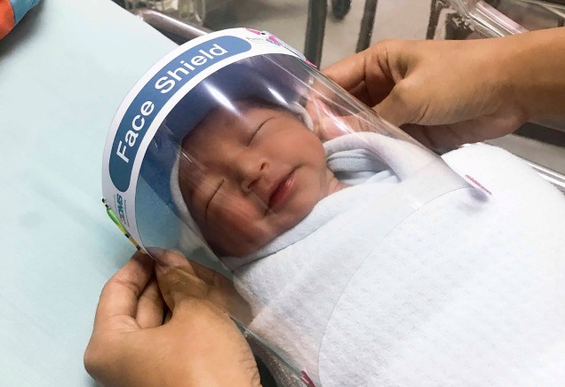 Hospital Samutprakarn, uma enfermeira ajusta o protetor facial em um bebê recém-nascido para proteger do novo coronavírus no berçário do hospital na província de Samutprakarn, centro da Tailândia. 03/04/2020 Hospital Samutprakarn, uma enfermeira ajusta o protetor facial em um bebê recém-nascido para proteger do novo coronavírus no berçário do hospital na província de Samutprakarn, centro da Tailândia. 03/04/2020