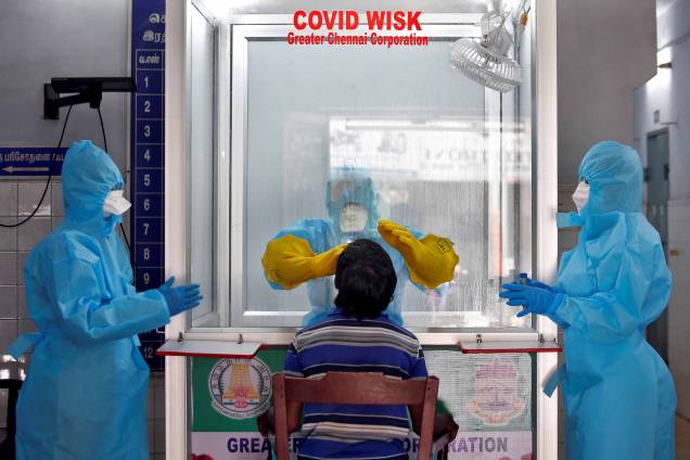 Um médico em uma câmara de proteção pega um cotonete de um homem para testar a doença de coronavírus (COVID-19), em Chennai, Índia, 13/04/2020.