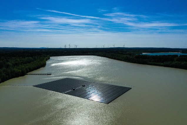 Vista aérea mostra painéis solares em uma usina fotovoltaica flutuante no lago Silbersee em Haltern, oeste da Alemanha, com turbinas eólicas à distância em 22/04/2022.