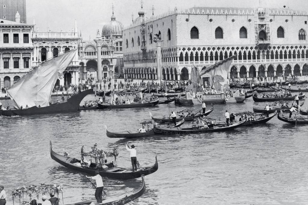 Between 1920 And 1930, The Gondoliers Carrying Tourists On The Lagoon In Front Of The Palazzo Ducale In Venice. TRÂNSITO DE GÔNDOLAS - Veneza em 1920: euforia após a gripe espanhola -