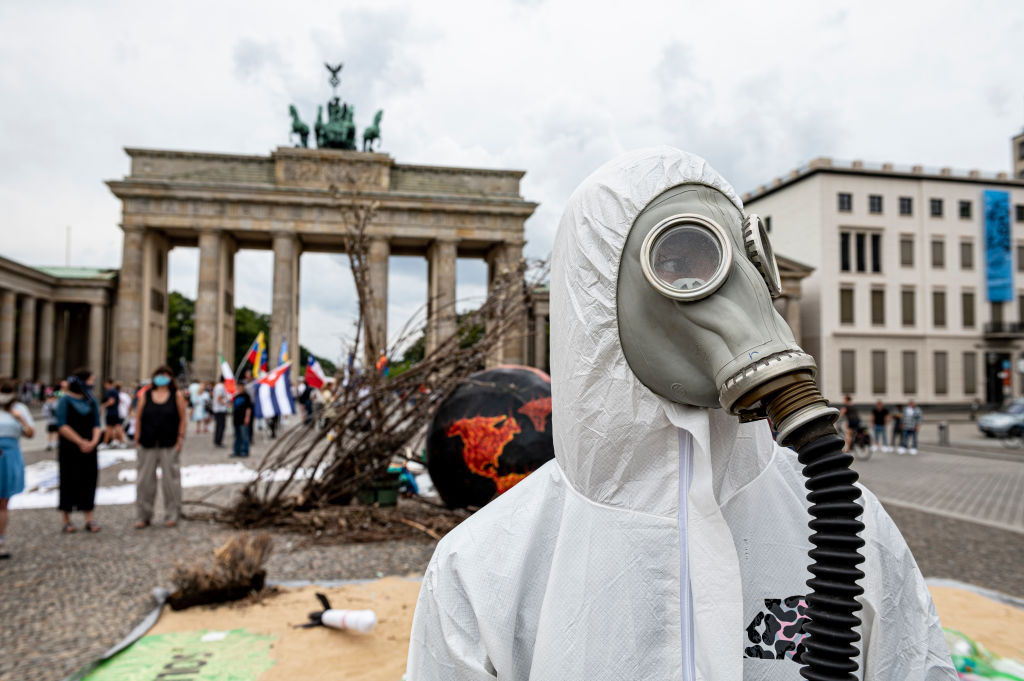 22 August 2020, Berlin: An activist from Extinction Rebellion wears a gas mask in front of the Brandenburg Gate on "Global Earth Overshoot Day". The environmentalists drew attention to the day on which, according to their calculations, all renewable resources in the current year would be used up. Photo: Fabian Sommer/dpa (Photo by Fabian Sommer/picture alliance via Getty Images)