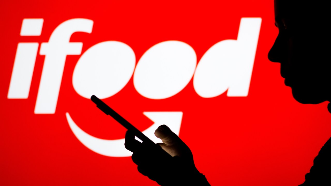 BRAZIL - 2022/04/18: In this photo illustration the iFood logo seen in the background of a silhouette woman holding a mobile phone. (Photo Illustration by Rafael Henrique/SOPA Images/LightRocket via Getty Images)