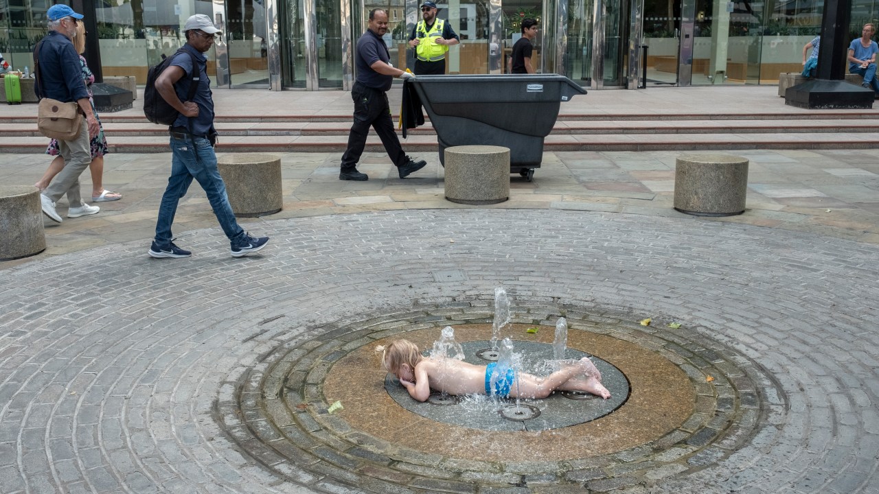 LONDON, ENGLAND - JULY 15: Felix Johnson, aged 3, cools off in a water fountain on the pavement at London Bridge on July 15, 2022 in London, England. Britain will experience a heatwave this week as temperatures in some parts are expected to exceed 30c. A level 2 heat health alert has been issued to south and eastern parts of England. (Photo by Bryn Colton/Getty Images)