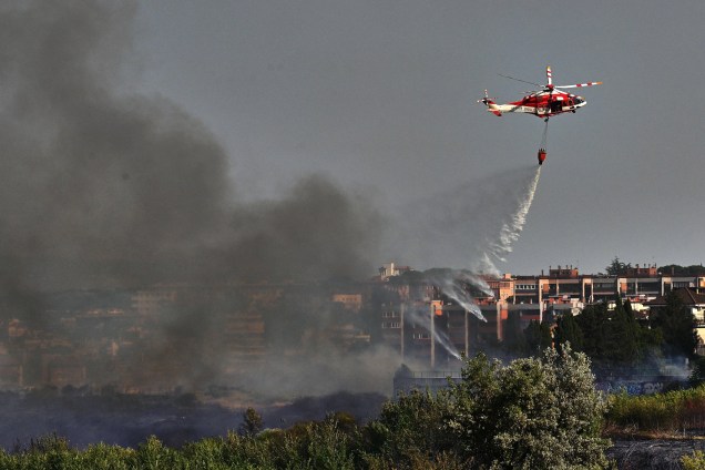 O helicóptero de um bombeiro jogando água para apagar um incêndio que eclodiu no parque Valle Aurelia, em Roma, em 04/07/2022.