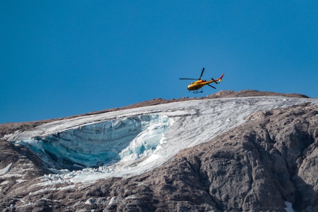 Um helicóptero de resgate sobrevoa sobre a geleira que desabou no dia anterior na montanha de Marmolada, a mais alta das Dolomitas, um dia após uma temperatura recorde ser registrada no cume da geleira.