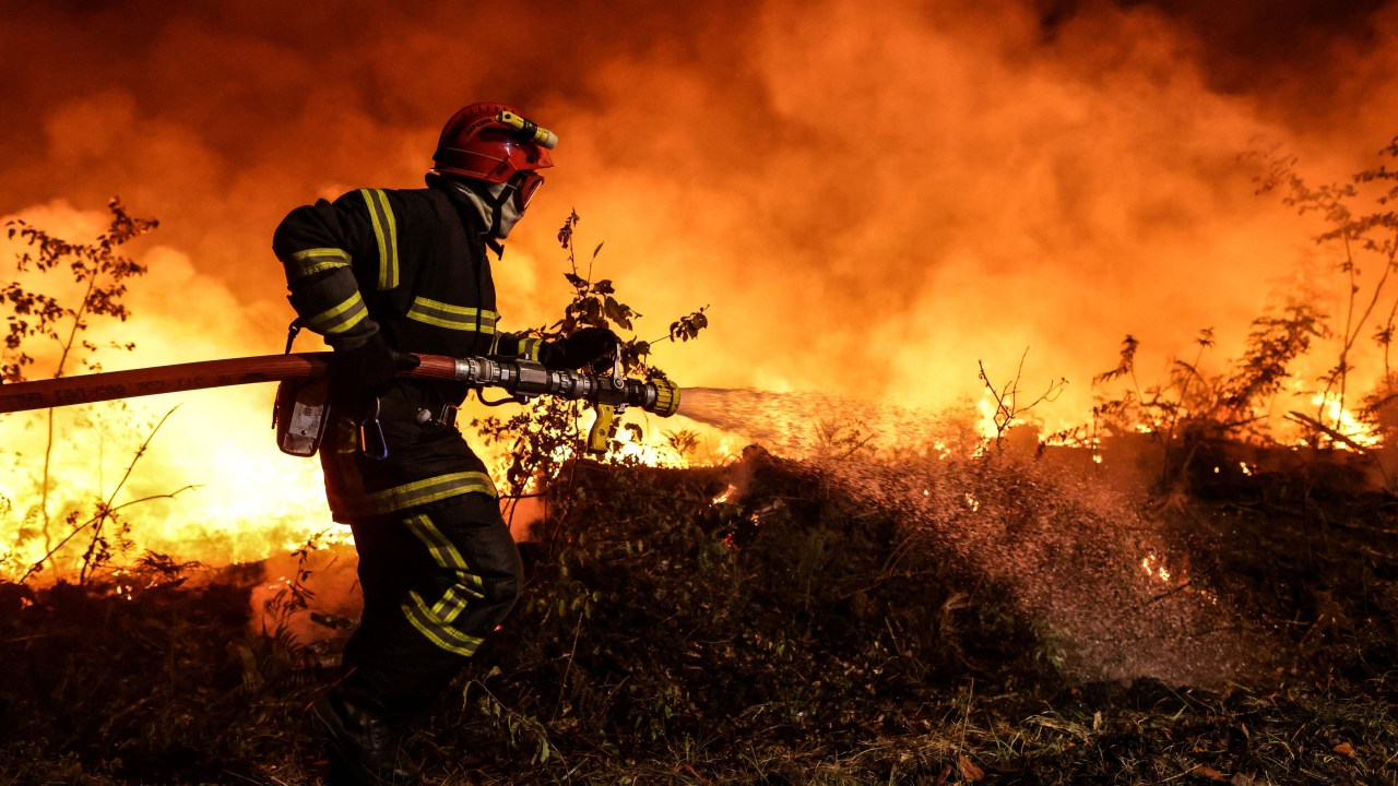 Um bombeiro apoiado por bombeiros táticos (invisíveis) ateou fogo controlado para queimar um pedaço de terra enquanto tentava impedir que o fogo se espalhasse devido à mudança do vento, enquanto lutavam contra um incêndio florestal perto de Louchats em Gironde, sudoeste da França, em 17 de julho de 2022. - A França estava em alerta máximo em 18 de julho de 2022, quando o pico de uma onda de calor castigava o país, enquanto os incêndios florestais em partes do sudoeste da Europa não mostravam sinais de diminuir. Na região sudoeste do Gironde, os bombeiros durante o fim de semana continuaram lutando para controlar as chamas florestais que devoraram quase 11.000 hectares (27.000 acres) desde 12 de julho. (Foto de THIBAUD MORITZ / AFP)