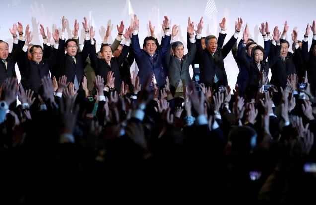 O ex primeiro-ministro do Japão, Shinzo Abe, que também é líder do Partido Liberal Democrático (LDP), grita 'Banzai', enquanto levanta as mãos com membros do LDP durante a convenção anual do partido em Tóquio, Japão, 25/03/2018.
