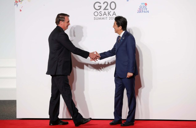 O presidente do Brasil, Jair Bolsonaro é cumprimentado pelo ex primeiro-ministro do Japão, Shinzo Abe em sua chegada ao encontro dos países do G20, em Osaka. 28/06/2019.