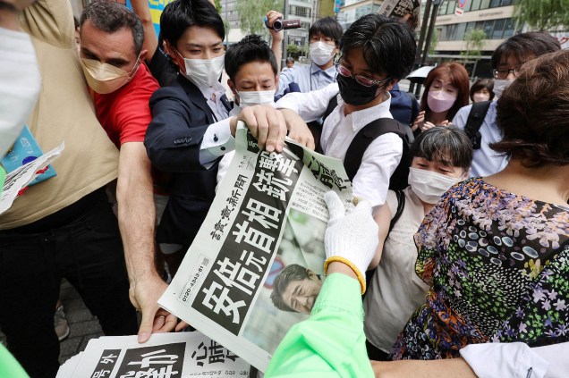 As pessoas se aglomeram para pegar um jornal extra sobre o assassinato do ex-primeiro-ministro japonês Shinzo Abe, em Tóquio /08/07/2022.