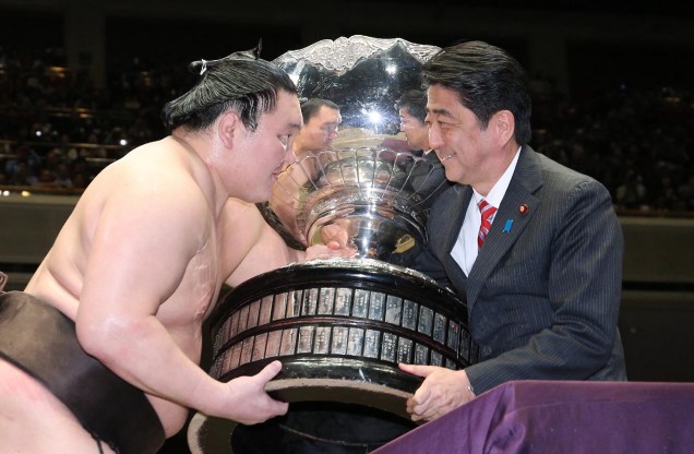 O grande campeão se Sumô "yokozuna", Hakuho, recebe a taça do ex primeiro-ministro  Shinzo Abe após vencer o torneio nacional de Sumô em Tóquio. 22/05/2016.